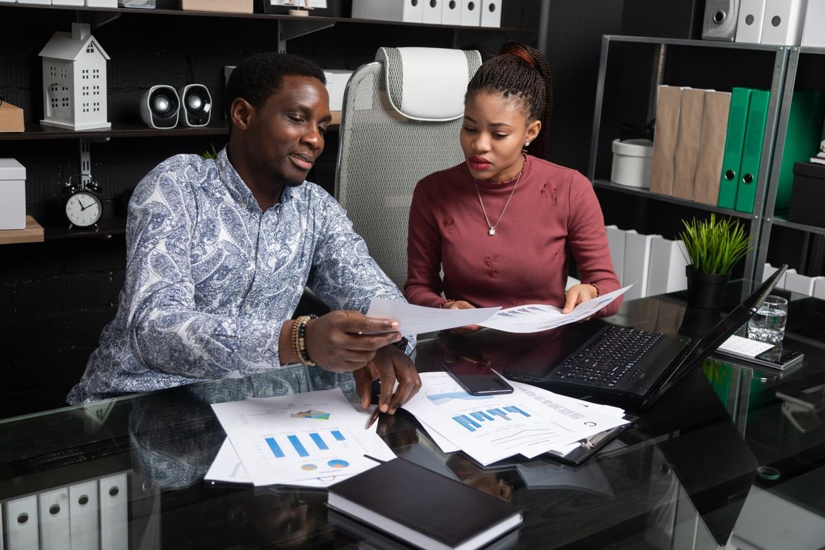 two young black people discuss their business using diagrams sitting at Desk in the office